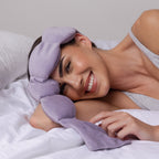 Woman wearing a purple sleep mask in bed