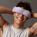 Person wearing a light purple sleep mask with a neutral background