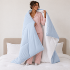 Woman holding open a reversible Baby Blue CloudSoft comforter to show the white reverse side