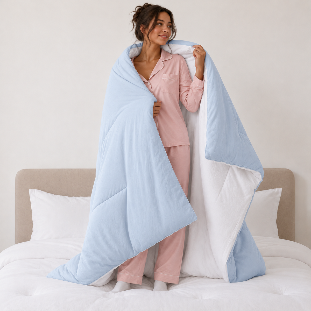 Woman holding open a reversible Baby Blue CloudSoft comforter to show the white reverse side