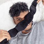 Person wearing a black sleep mask in bed
