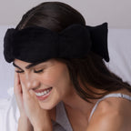 Woman wearing a black headband with a bow, smiling.