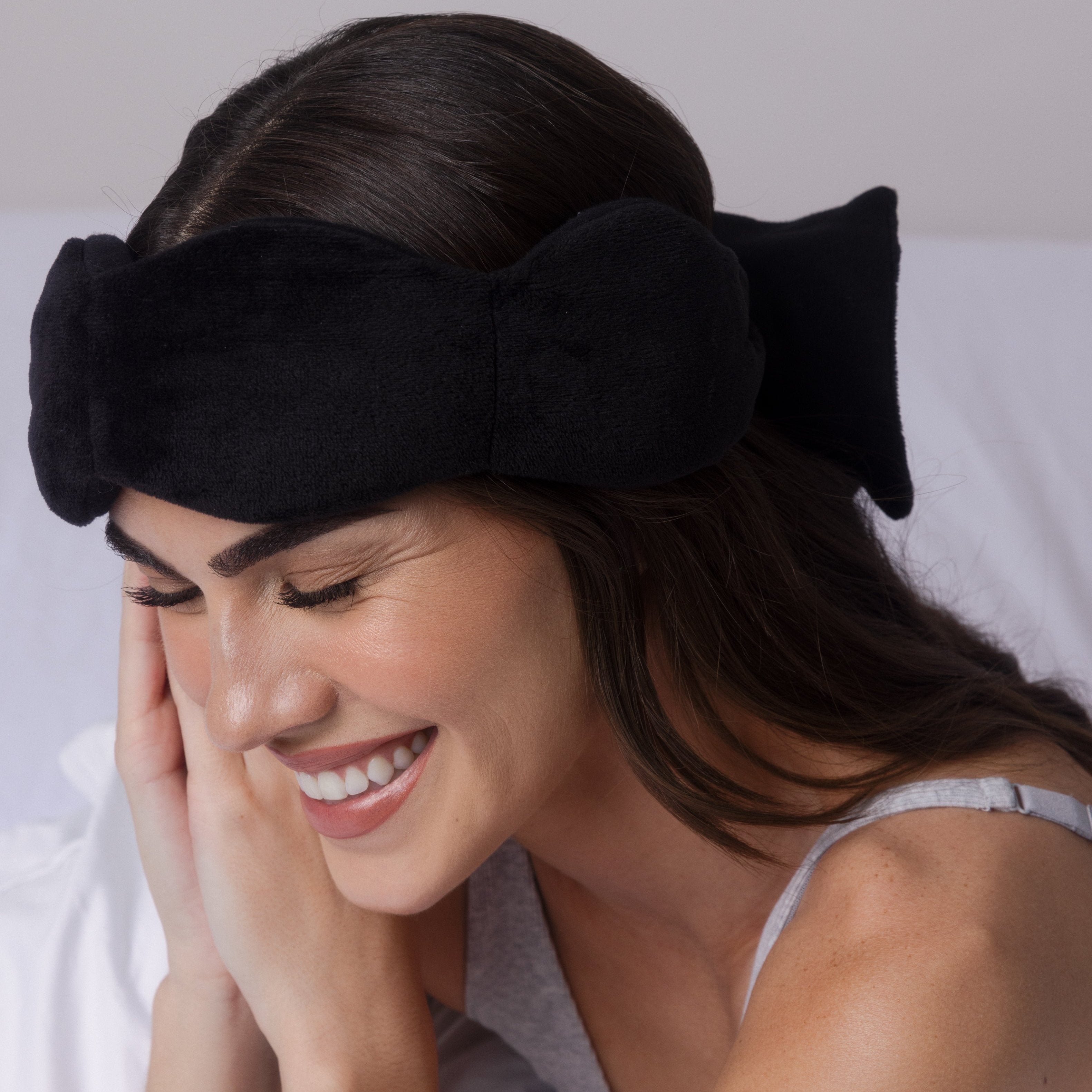 Woman wearing a black headband with a bow, smiling.