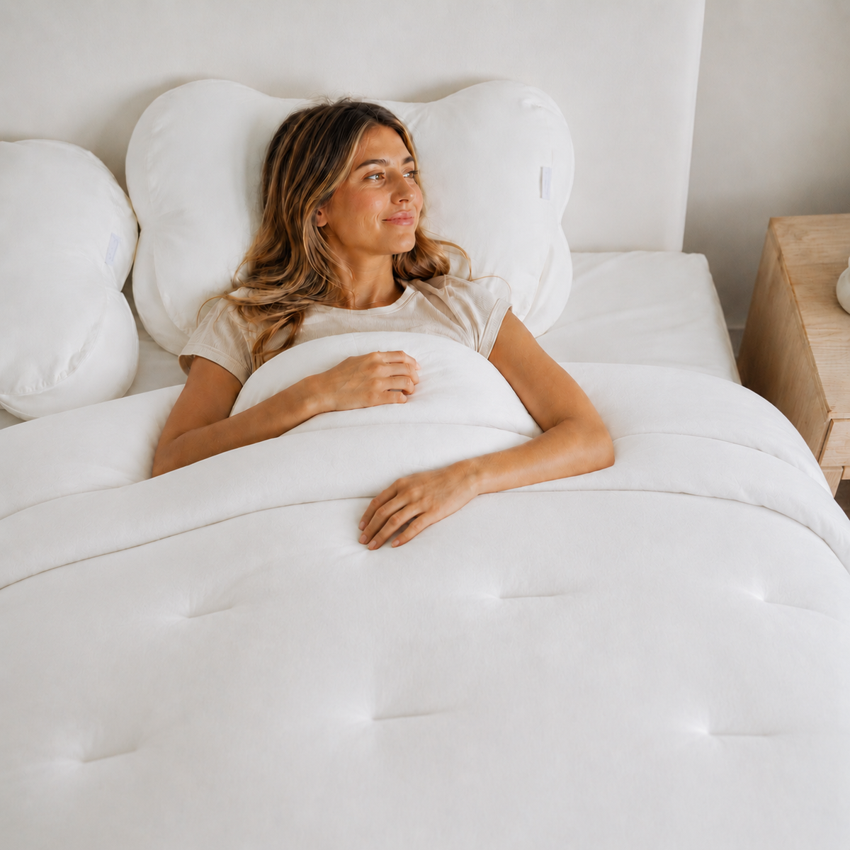 Woman lying in bed with white bedding and pillows