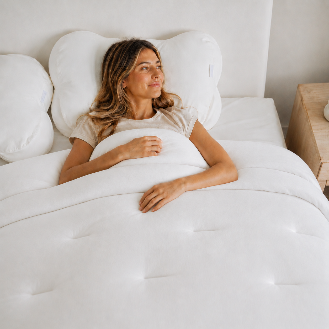Woman lying in bed with white bedding and pillows