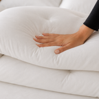 Hand touching a white comforter on a bed