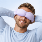 Man wearing a light purple sleep mask with a plain background