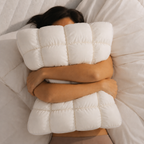 Person hugging a large white pillow in bed